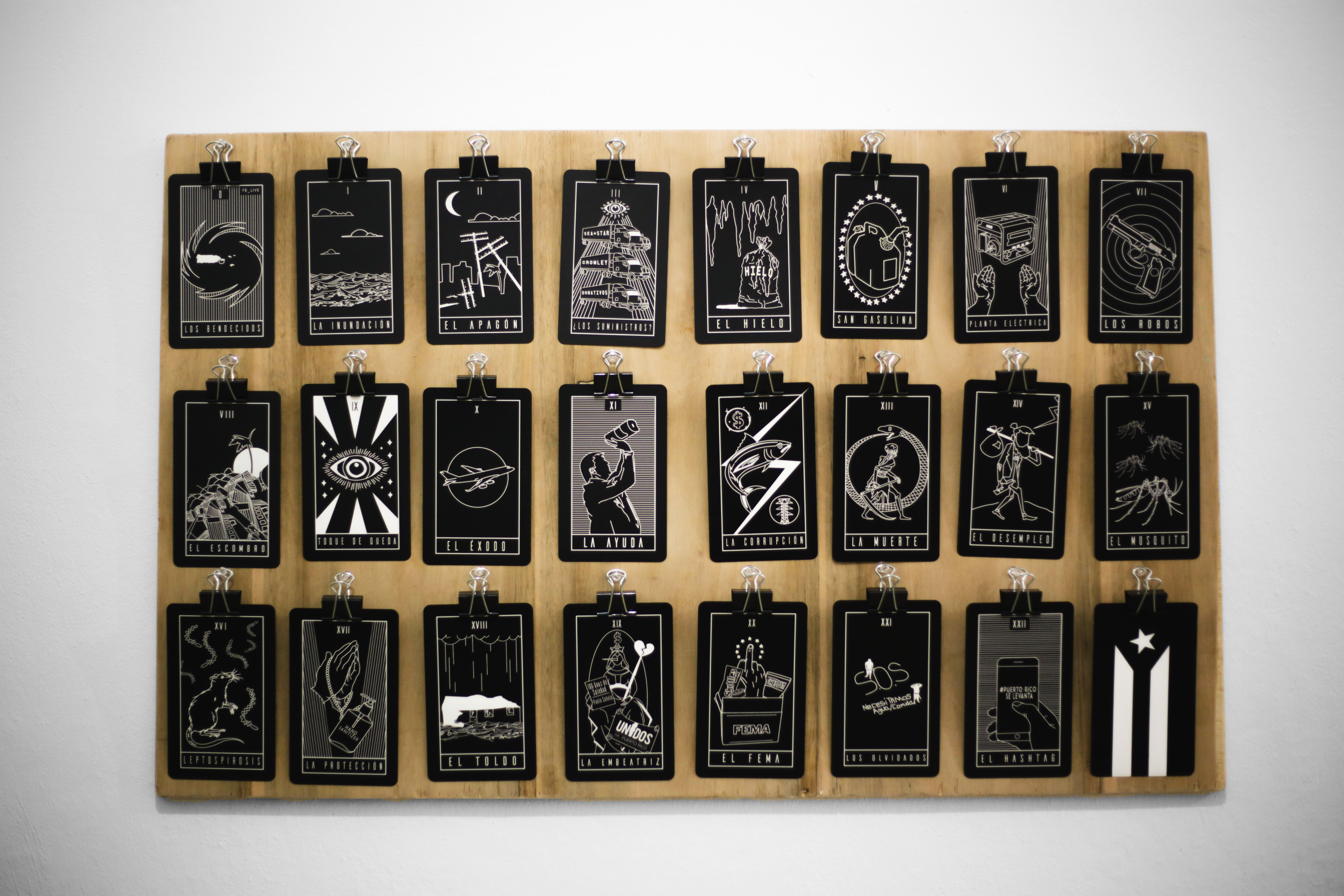 the black-and-white tarot cards trace Hurricane María's narrative while clipped to a wooden board for display